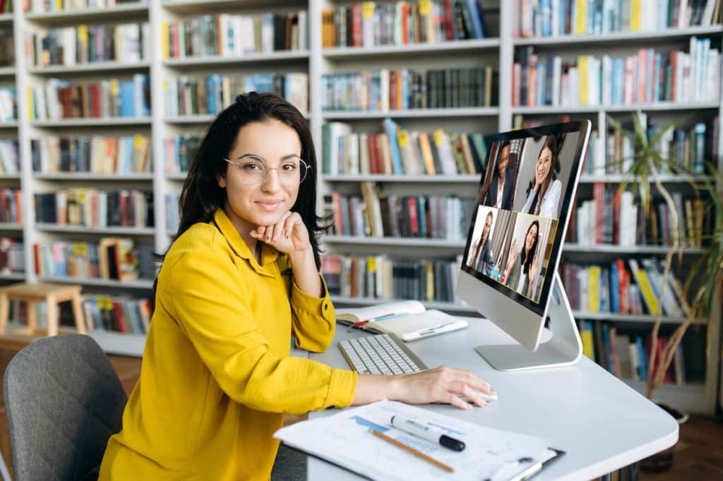 Young woman sitting at a desk on a video call with colleagues.
