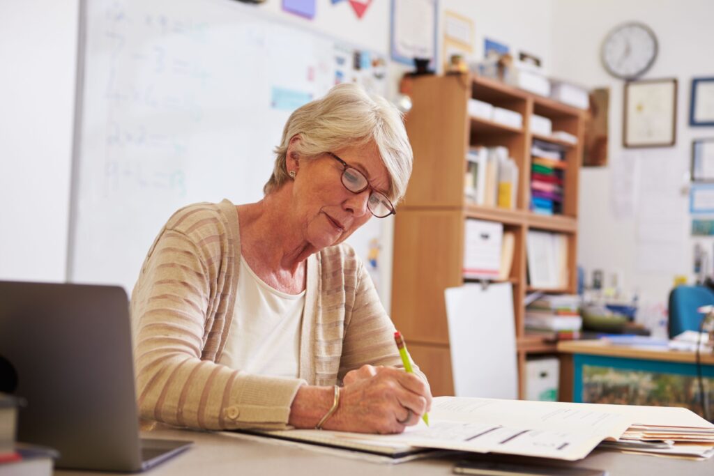 A teacher works on lesson planning at her classroom desk.