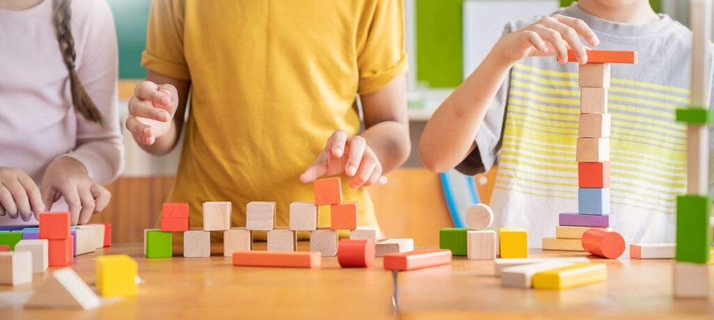 A close-up of children’s hands playing with blocks.