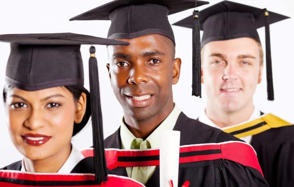 Group of doctoral graduates posing for a picture in their caps and gowns.