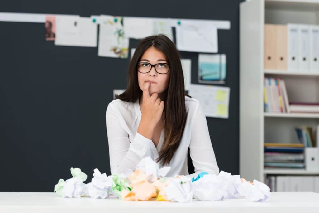 Young women sitting at a desk thinking about something.
