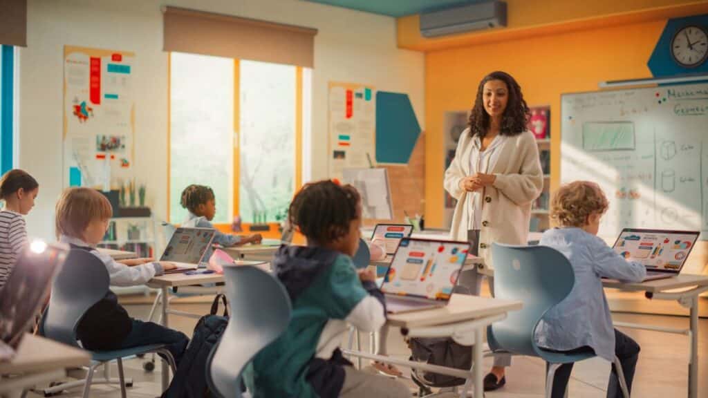 A teacher stands in front of the elementary classroom teaching.