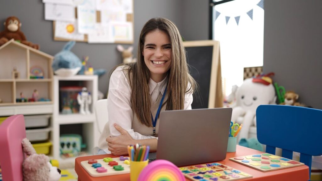A teacher sits at her computer in her classroom, symbolizing receiving her online Master of Arts in Teaching.