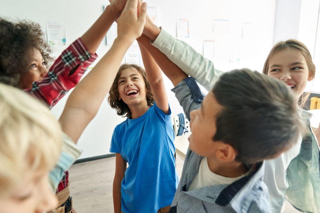 A group of students happily high-five.