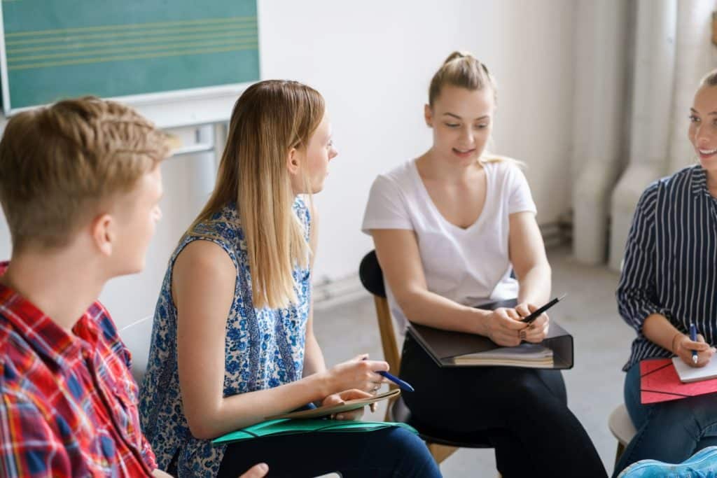 Group of students and a teacher sitting in a circle and talking.