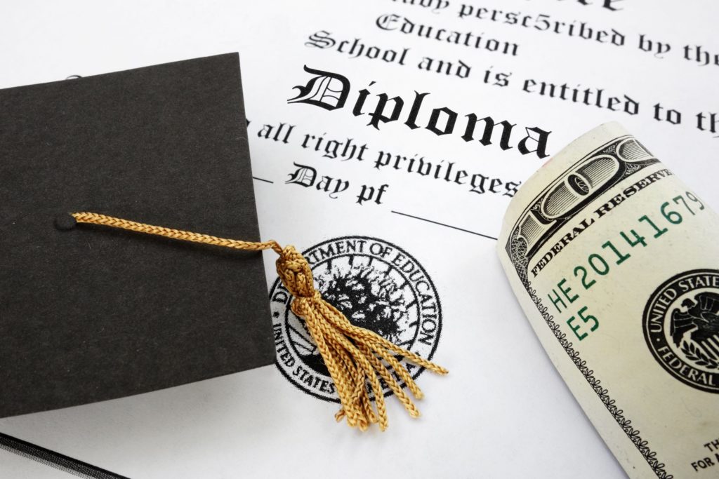 Graduation cap and money on a diploma.