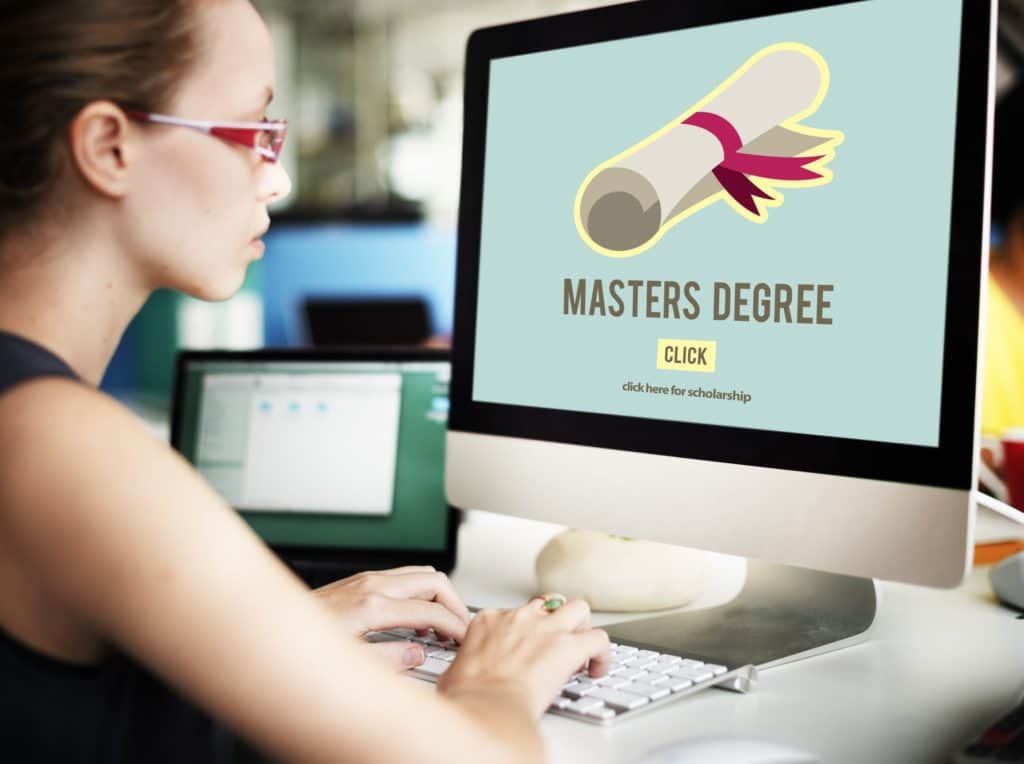 Young woman sitting at a computer looking at a master’s degree.