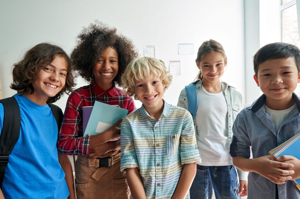 A group of middle school students stand together in a classroom.