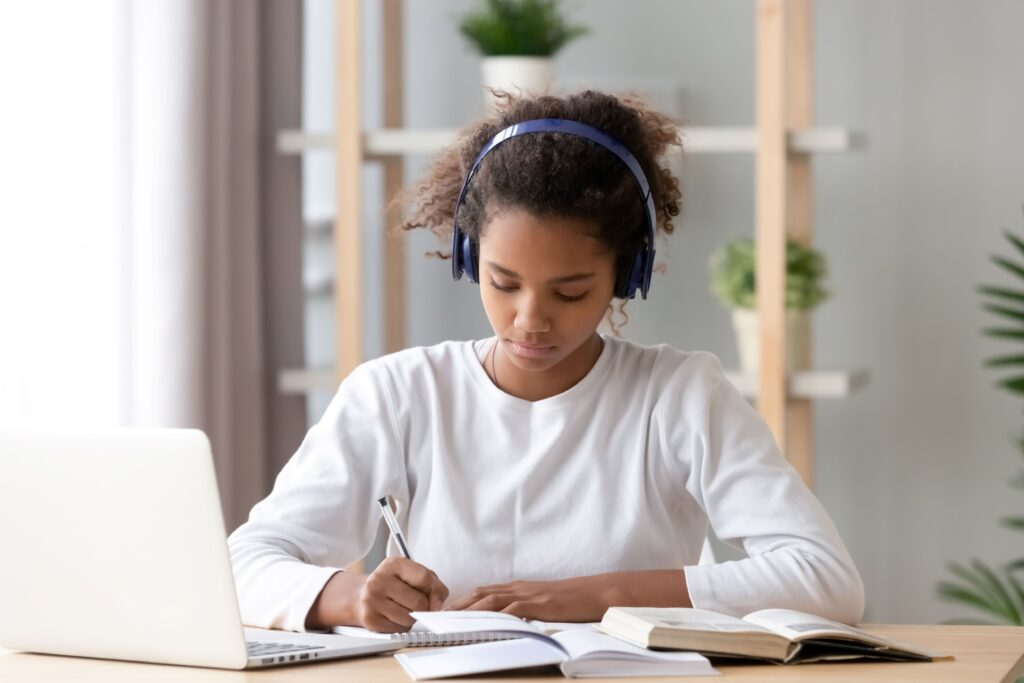 A student sits at her desk at home and works on homework.