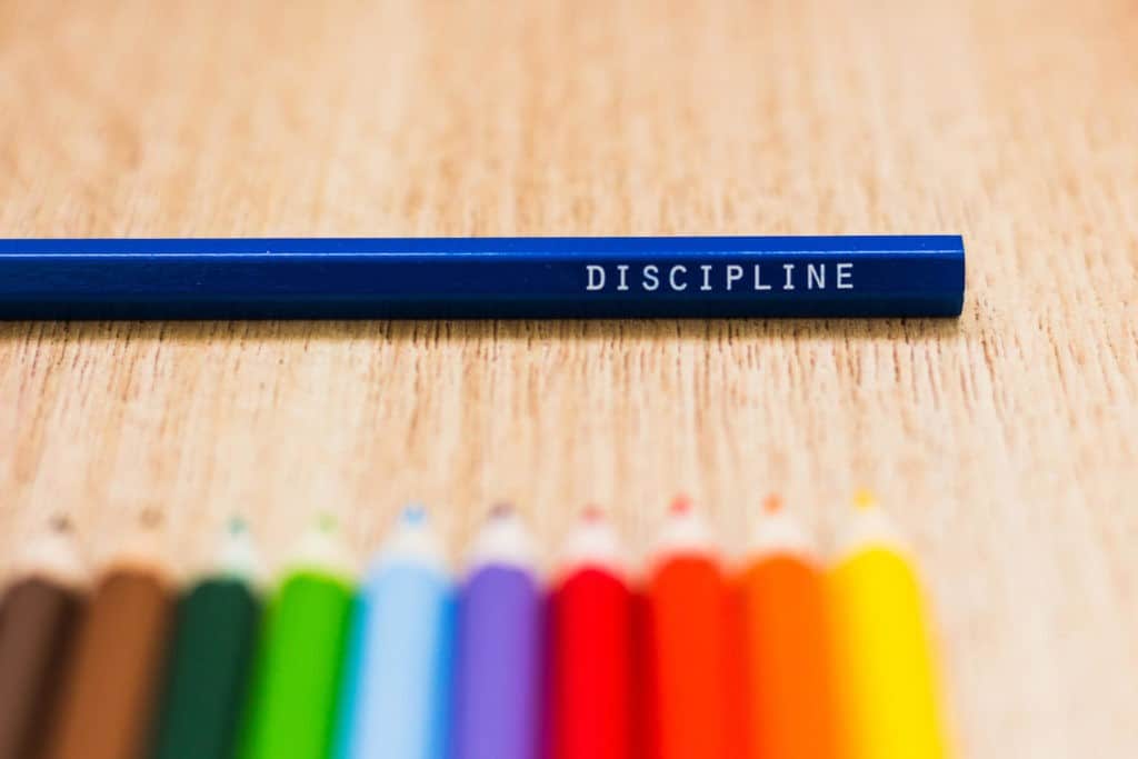 ‘Discipline’ on a blue clored pencil around other colored pencils.