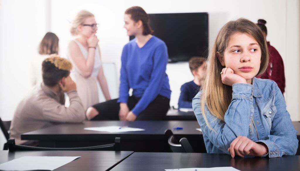 A student sits away from her classmates by herself.