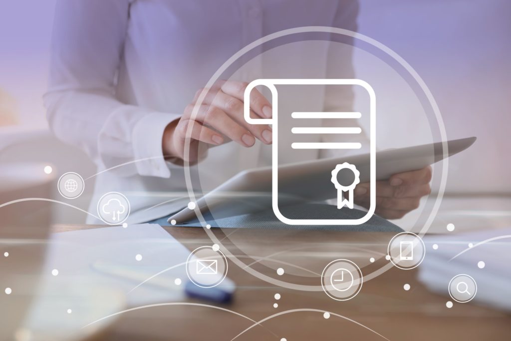 A woman holds an iPad in the foreground, behind a certificate icon.