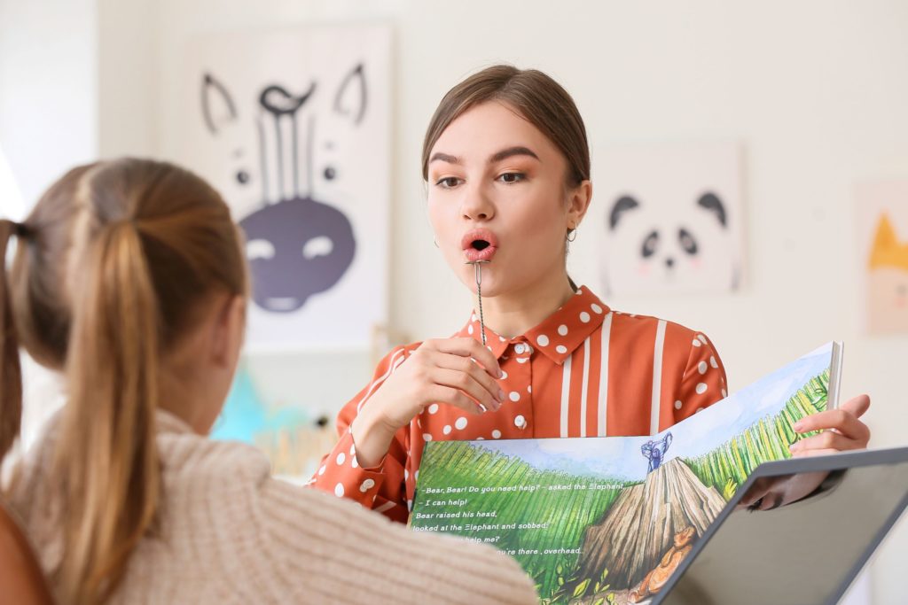 A speech pathologist works with a young girl.
