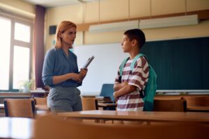 A student meets with his teacher one-on-one after all other students are gone; she looks concerned.